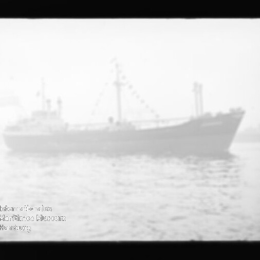 Verschwommene Silhouette eines Frachtschiffs mit Masten und einer Kette aus Signalflaggen auf ruhigem, nebligem Wasser, unten links ein rundes Museumswasserzeichen.