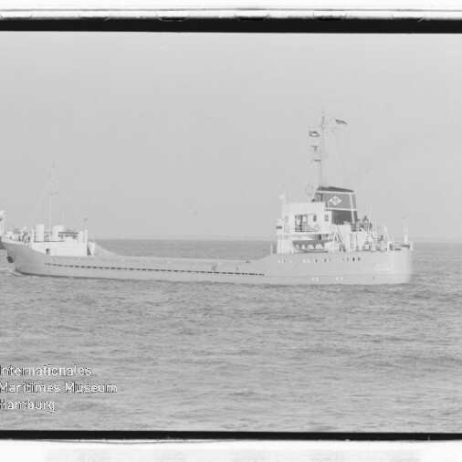 Schwarz-weiße Aufnahme zweier Frachtschiffe auf ruhiger See: im Vordergrund ein langes Frachtschiff mit Aufbauten am Heck und Schornstein mit Logo, im Hintergrund links ein weiteres Schiff; unten links Schriftzug des Internationalen Maritimen Museums Hamburg und sichtbarer Negativrahmen.