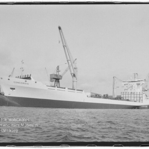 Schwarzweiß-Foto eines Frachtschiffs mit dem Namen CONCORDIA, das an einem Hafenpier liegt, umgeben von großen Hafenkränen und ruhiger Wasseroberfläche; im unteren linken Bildbereich das Logo und der Schriftzug des Internationalen Maritimen Museums Hamburg.