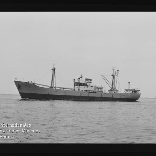 Schwarzweiß-Foto eines seitlich aufgenommenen Frachtschiffs mit Ladekränen und Aufbauten auf ruhiger See, weiter Horizont und Wasserzeichen des Internationalen Maritimen Museums Hamburg unten links.