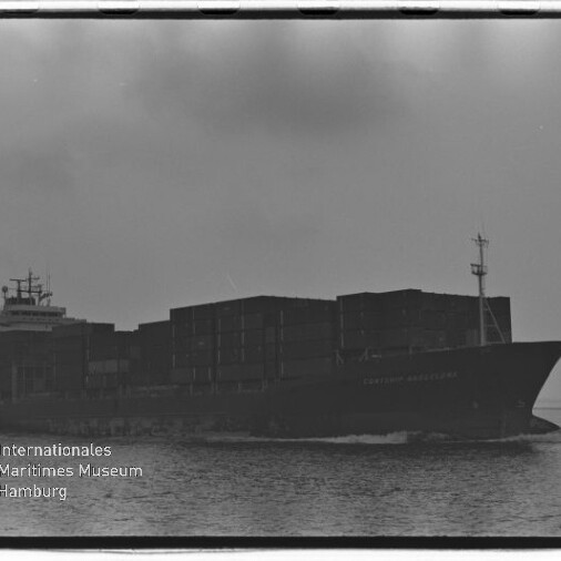 Schwarzweißfoto eines beladenen Containerschiffs in Seitenansicht, das mit mehreren Containerstapeln über ruhigem Wasser fährt; unten links ist das Logo und der Schriftzug des Internationalen Maritimen Museums Hamburg zu sehen.