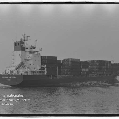 Schwarzweiß-Foto eines beladenen Containerschiffs auf ruhiger See mit mehreren gestapelten Seecontainern, sichtbarem Filmrahmen und Wasserzeichen des Internationalen Maritimen Museums Hamburg unten links.