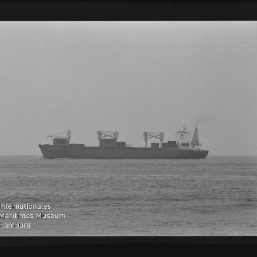 Schwarzweiß-Foto eines Containerschiffs in Seitenansicht auf ruhiger See, sichtbar sind mehrere Ladekräne auf dem Deck, der Filmrand mit Aufdruck 'AGFAPAN 100' und ein Wasserzeichen des Internationalen Maritimen Museums Hamburg im Bild