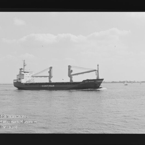Schwarzweißaufnahme eines Frachtschiffs mit dem Schriftzug CONTIMAR und zwei Ladekränen an Deck, das über ruhige See vor flachem Horizont fährt; Filmrand und Wasserzeichen des Internationalen Maritimen Museums Hamburg sind sichtbar.