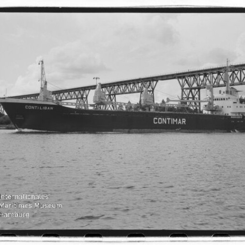 Schwarzweißaufnahme eines großen Frachtschiffs mit dem Namen CONTIMAR, das auf ruhigem Wasser unter einer hohen Stahlfachwerkbrücke entlangfährt; unten links sichtbar das Wasserzeichen des Internationalen Maritimen Museums Hamburg.