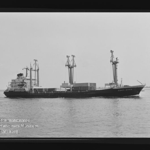 Schwarzweißfoto eines Frachtschiffs mit drei Ladekränen und Containern an Deck, das ruhig auf dem Wasser fährt; Filmrand und Logo des Internationalen Maritimen Museums Hamburg sind sichtbar.