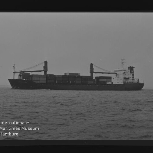 Schwarzweiß-Seitenansicht eines beladenen Containerschiffs mit zwei Ladekränen und achterlicher Aufbauten auf ruhiger See, umgeben von schwarzem Filmrand mit Kodak-Schriftzug und Wasserzeichen des Internationalen Maritimen Museums Hamburg.