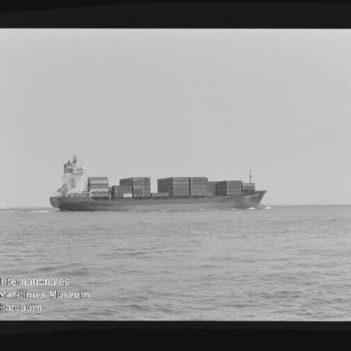 Schwarzweiß-Seitenansicht eines beladenen Containerschiffs mit übereinander gestapelten Containern, das auf ruhiger See nach rechts fährt; schwarzer Bildrand und Wasserzeichen des Internationalen Maritimen Museums Hamburg links unten.