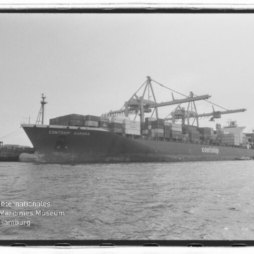 Schwarzweißaufnahme des Containerschiffs Contship Aurora am Kai, beladen mit gestapelten Containern und umgeben von großen Containerkränen, mit Wasser im Vordergrund und Museumswasserzeichen unten links.