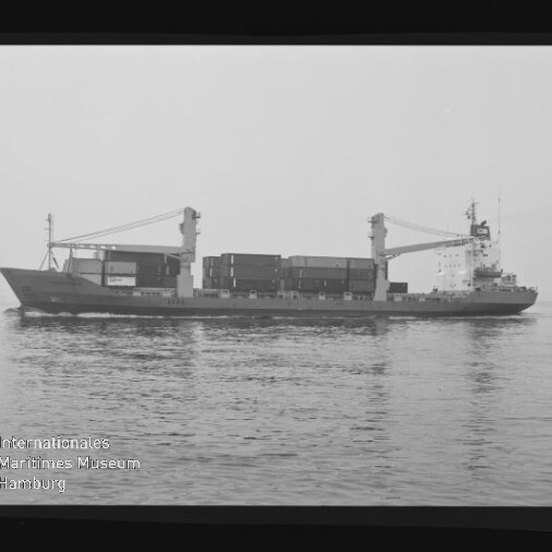 Schwarz-weiß-Seitenansicht eines Containerfrachtschiffs mit zwei Ladekränen und gestapelten Containern, das ruhig auf dem Meer liegt; Wasserzeichen des Internationalen Maritimen Museums Hamburg unten links.
