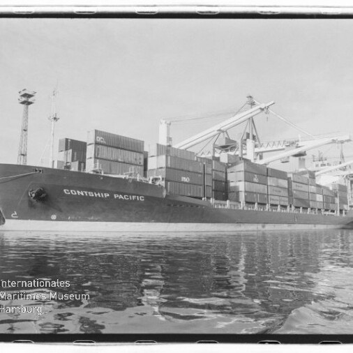 Schwarzweißaufnahme des Containerschiffs 'CONTSHIP PACIFIC' am Kai, beladen mit gestapelten Containern, umgeben von Hafenkranen und mit Reflexion im Wasser; links unten das Logo des Internationalen Maritimen Museums Hamburg.