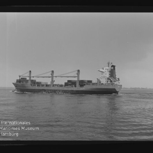 Schwarzweiß-Seitenansicht eines mit Containern beladenen Containerschiffs mit zwei Ladekränen auf ruhiger See, im Vordergrund Wasser und unten links das Logo des Internationalen Maritimen Museums Hamburg.