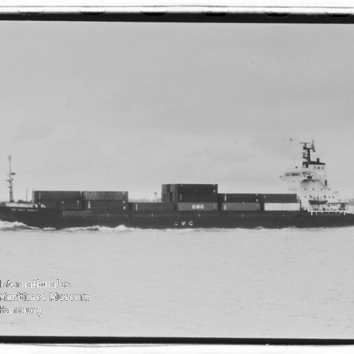 Schwarzweiß-Aufnahme eines Containerschiffs in Seitenansicht mit gestapelten Seecontainern auf ruhiger See; unten links sichtbar das Wasserzeichen des Internationalen Maritimen Museums Hamburg.