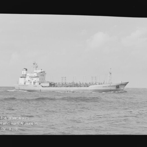 Schwarzweißaufnahme eines Frachtschiffs (Tankers) mit achterlichem Aufbauten und mehreren Decksmasten, das auf leicht gewellter See fährt; Negativrahmen mit Filmkantenmarkierungen und ein Wasserzeichen des Internationalen Maritimen Museums Hamburg unten links sichtbar.