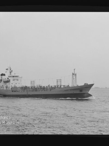 Schwarzweiß-Seitenansicht eines Tankschiffs auf ruhiger See mit Aufbauten achtern und sichtbaren Rohrleitungen auf dem Deck, weiter Horizont im Hintergrund und einem weißen Logo des Internationalen Maritimen Museums Hamburg unten links.