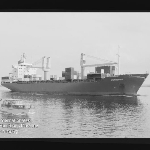 Schwarz-weiß-Foto eines Containerschiffs mit dem Schriftzug CORONA, beladen mit Containern und sichtbaren Ladekränen, das auf ruhigem Wasser vorbeifährt; im Vordergrund ein kleines Motorboot sowie Filmrand und Museumswasserzeichen am Bildrand sichtbar.