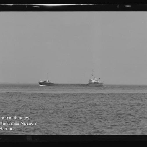 Schwarzweiß-Fotografie zweier Handelsschiffe auf ruhiger See nahe dem Horizont, links ein niedriger Frachter, rechts ein Schiff mit höherem Aufbauten; unten links Logo und Schriftzug des Internationalen Maritimen Museums Hamburg.