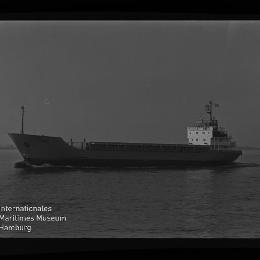 Schwarzweiß-Seitenansicht eines Frachtschiffs auf ruhiger See mit Aufbauten am Heck; unten links Logo und Schriftzug des Internationalen Maritimen Museums Hamburg.