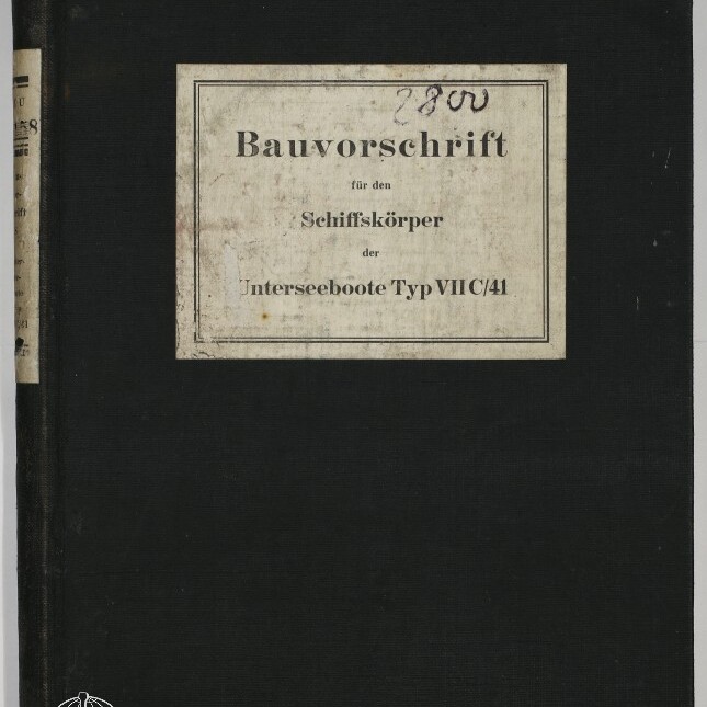 Schwarzer Leineneinband eines technischen Handbuchs mit weißem Etikett in der Mitte, darauf der gedruckte Titel ‚Bauvorschrift für den Schiffskörper der Unterseeboote Typ VIIC/41‘ sowie eine handschriftliche Ziffer oben, unten links das Logo und der Schriftzug Internationales Maritimes Museum Hamburg.