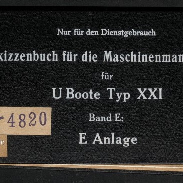 Schwarzer, querformatiger Deckel eines gebundenen Skizzenbuchs mit weißer Serifenschrift, oben die Aufschrift Nur für den Dienstgebrauch und Hauptausfertigung IV, mittig der Titel Skizzenbuch für die Maschinenmannschaft für U‑Boote Typ XXI Band E: E Anlage, links ein beigefarbenes Etikett mit der Signatur IV D 73–4820, eine Metallniete an der linken Kante und links unten das Logo des Internationalen Maritimen Museums Hamburg.