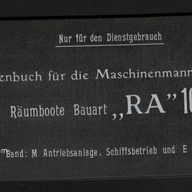Schwarzer Buchdeckel mit weißer deutscher Beschriftung ‚Nur für den Dienstgebrauch‘ und dem Titel ‚Skizzenbuch für die Maschinenmannschaft für Räumboote Bauart „RA“ 101‘, darunter Zusatzangaben zu Band/Antriebs‑ und Schiffsbetrieb; links zwei Metall-Scheiben zur Bindung und Logo des Internationalen Maritimen Museums Hamburg.