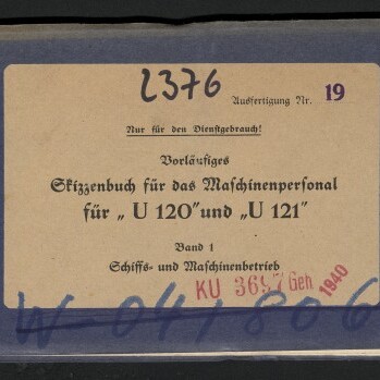 Langes, schmales, dunkelblaues Heft mit beigefarbenem Etikett in der Mitte, auf dem ein gedruckter deutscher Titel für ein Skizzenbuch des Maschinenpersonals zu den U‑Booten „U 120“ und „U 121“ steht; das Etikett zeigt handschriftliche Zahlen, rote Stempel und schwarze Markierungen, links unten das Logo des Internationalen Maritimen Museums Hamburg.