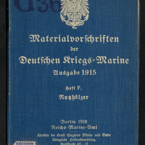 Blaue Leinenbroschur mit weißem kaiserlichem Adler und in Frakturschrift gedrucktem Titel ‚Materialvorschriften der Deutschen Kriegs‑Marine Ausgabe 1915‘, Verlagsangaben ‚Berlin 1916 Reichs‑Marine‑Amt‘, gestempelte Kennzeichnung ‚G36‘ oben links, Museumssiegel und kleines Markenetikett unten links sowie leicht abgewetzte Ecken.