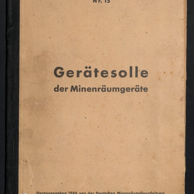 Verblasstes beigefarbenes Buch mit schwarzem Rücken, Titel groß in der Mitte: „Gerätesolle der Minenräumgeräte“, oben „Deutsche Minenräumdienstvorschrift Nr. 15“, unten Verlagsangabe 1946 und Museumssignet.