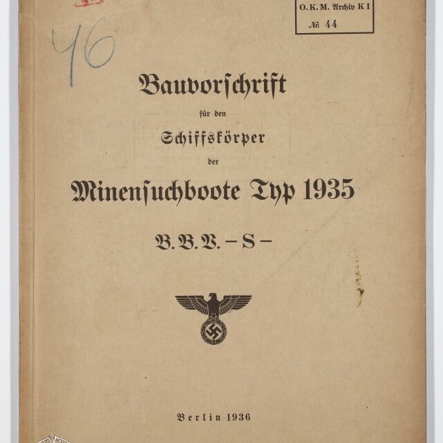 Gealtertes beige Buchcover mit der Titelaufschrift ‚Bauvorschrift für den Schiffskörper der Minensuchboote Typ 1935 B.B.V.-S-‘, gestempelt ‚Berlin 1936‘, einem nationalsozialistischen Reichsadler über Hakenkreuz, handschriftlichen Notizen oben und einem Museumsstempel unten links.