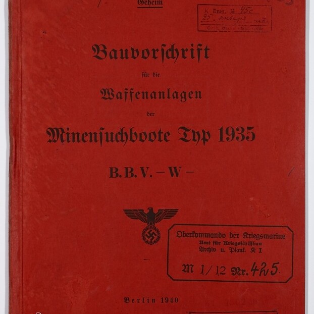 Rotes Deckblatt eines 1940 in Berlin erschienenen Dokuments mit dem Titel Bauvorschrift für die Waffenanlagen der Minensuchboote Typ 1935 in schwarzer Frakturschrift, versehen mit NS-Adler und Hakenkreuzstempel, mehreren Dienststempeln, handschriftlichen Nummern und dem Logo des Internationalen Maritimen Museums Hamburg unten links.