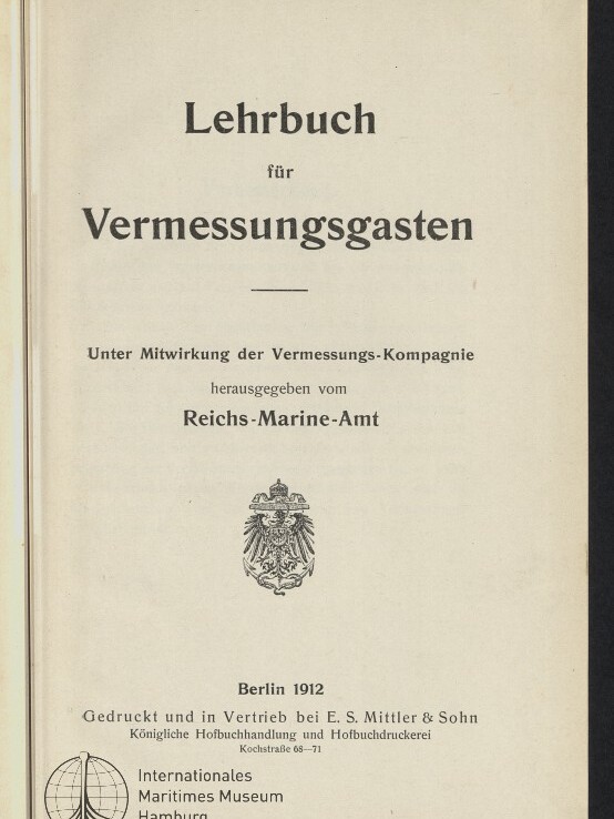 Titelseite eines Buchs mit der Überschrift „Lehrbuch für Vermessungsgasten“, Herausgeberangabe „Reichs-Marine-Amt“, einem kaiserlichen Wappen, der Angabe „Berlin 1912“ sowie einem Stempel/Logo des Internationalen Maritimen Museums Hamburg.