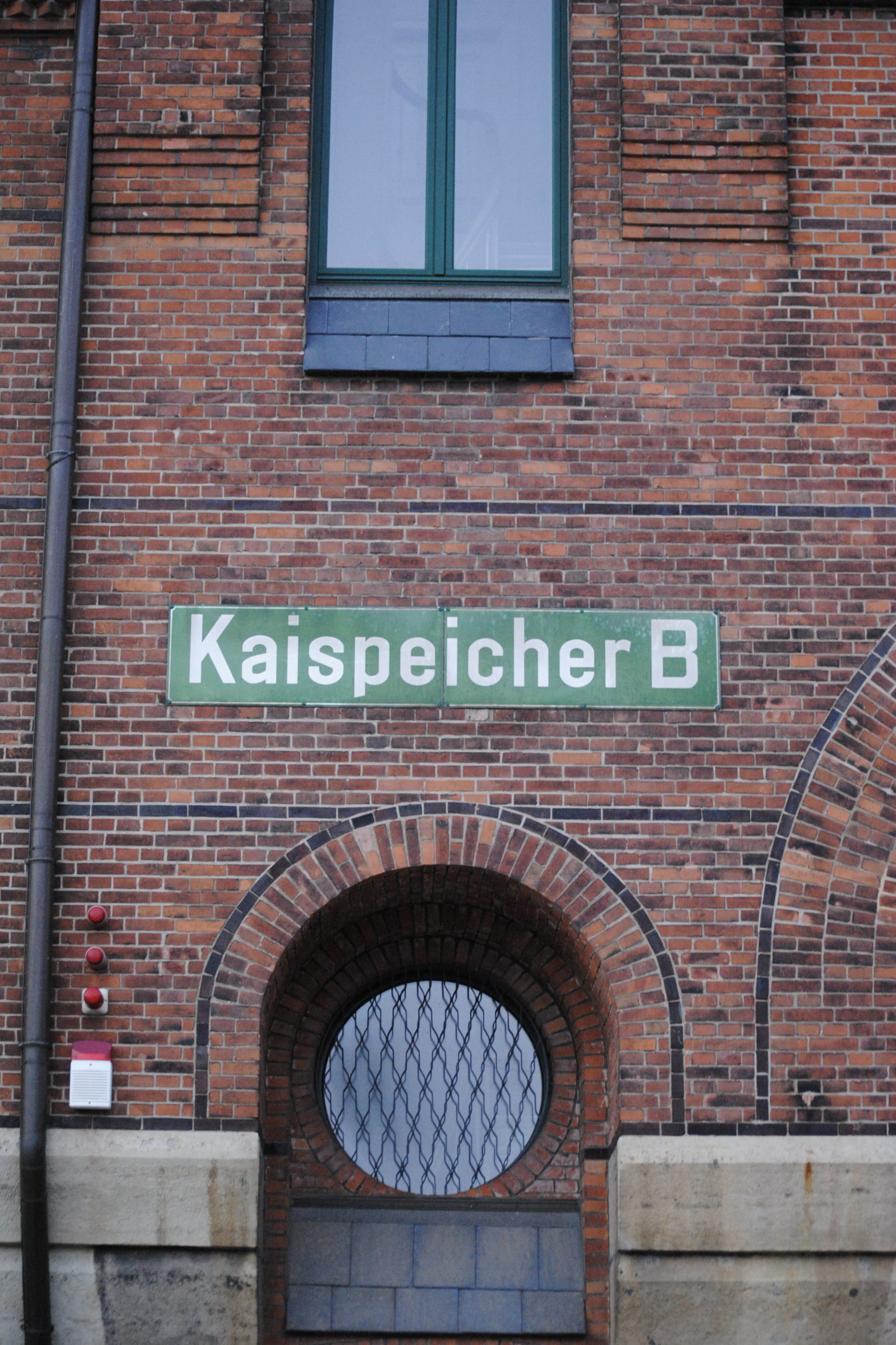 Rote Backsteinfassade mit grünem Schild 