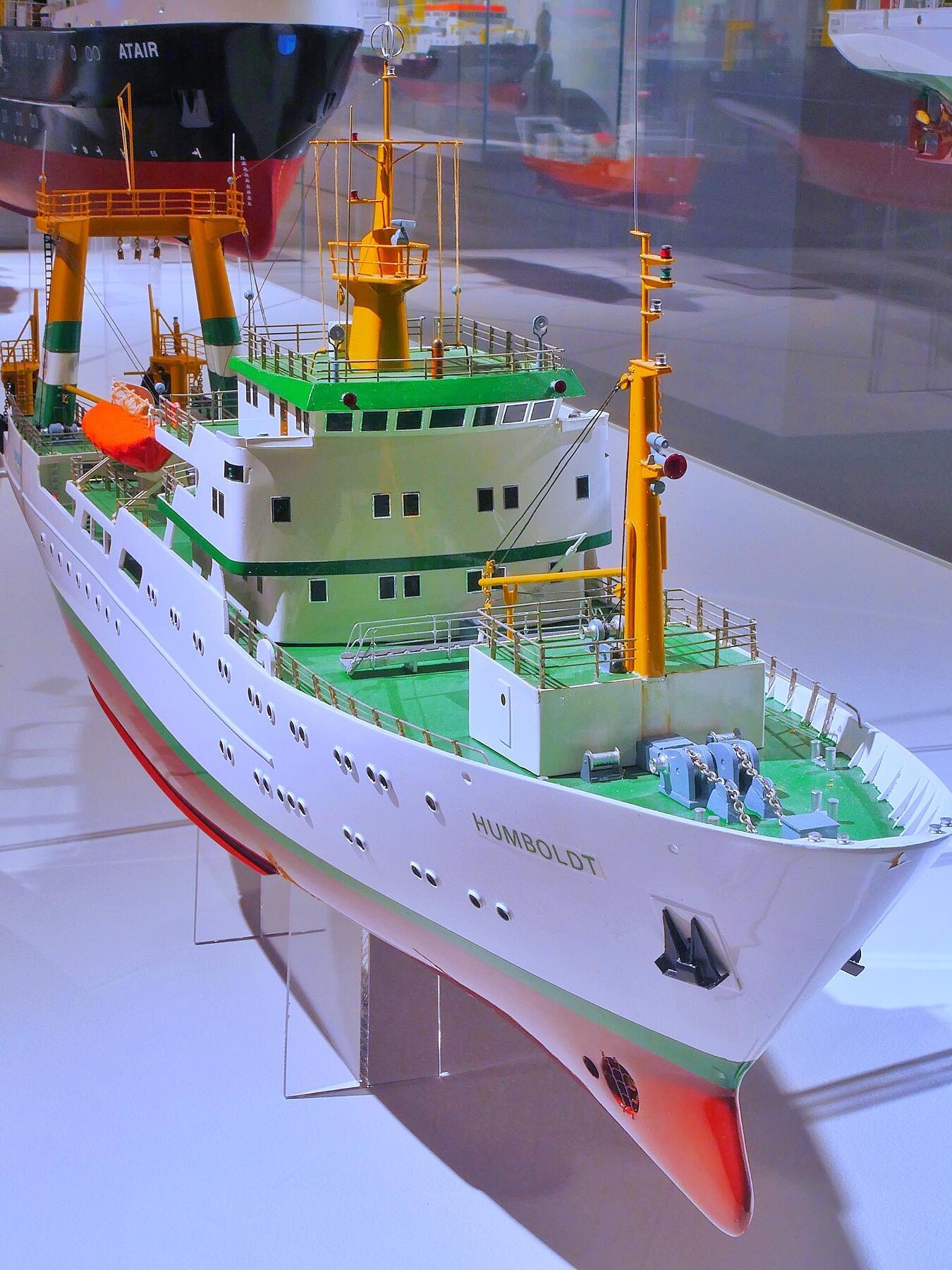 Modell eines weißen Forschungsschiffs mit grünem Deck, gelben Masten und dem Namen HUMBOLDT am Bug, gezeigt in einer Vitrine