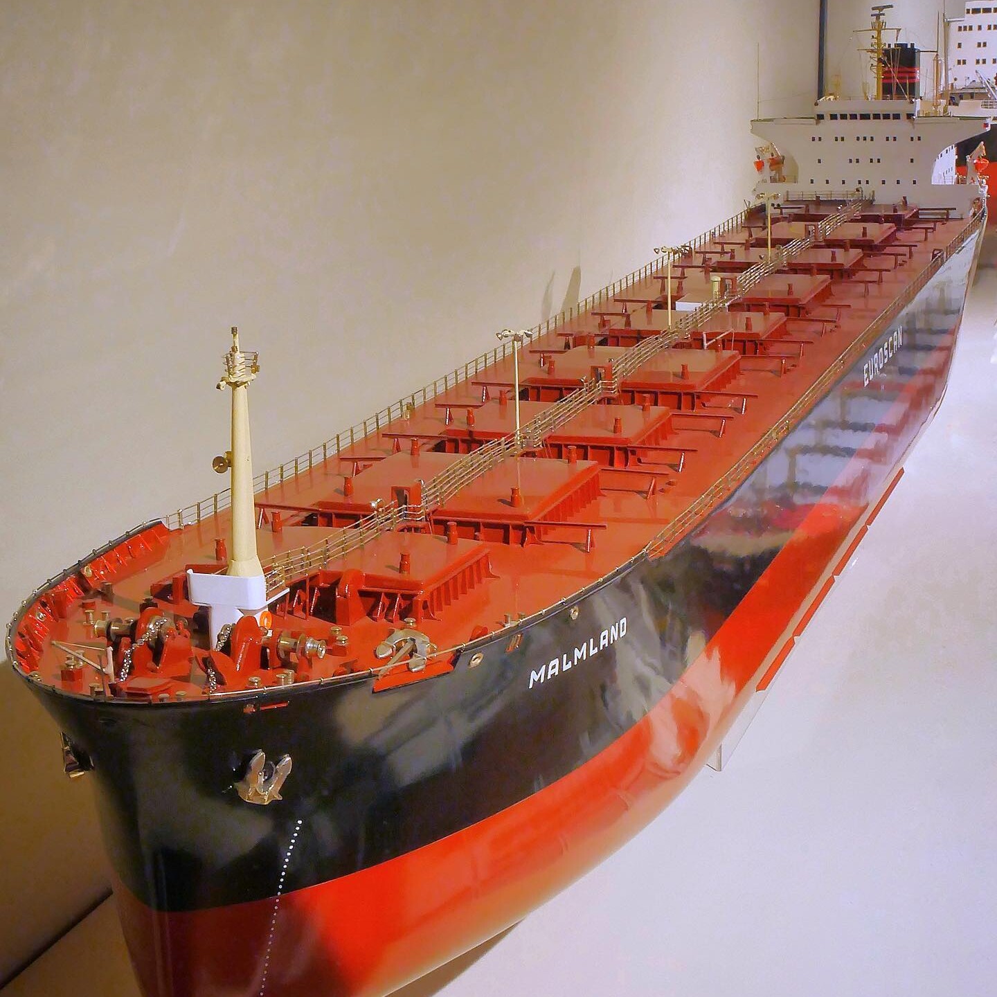 Modell eines großen Frachtschiffs mit rotem Deck und schwarzem Rumpf, Name MALMLAND an der Seite sichtbar, Nahaufnahme von Bug bis Aufbauten.