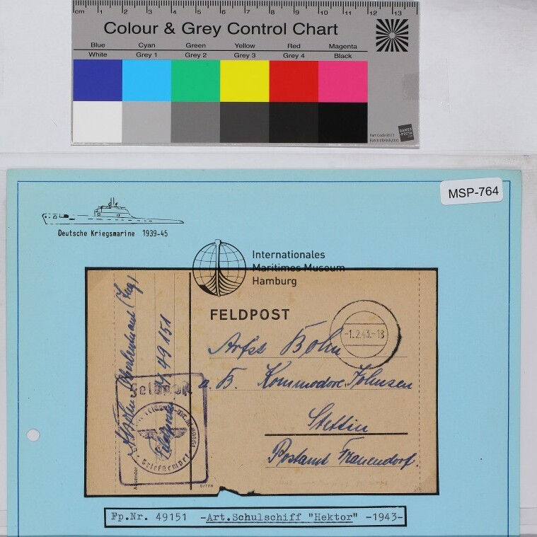 Auf blauem Archivblatt montierte Feldpostkarte mit handschriftlicher Adresse, Stempeln und aufgedrucktem Museumssiegel.
