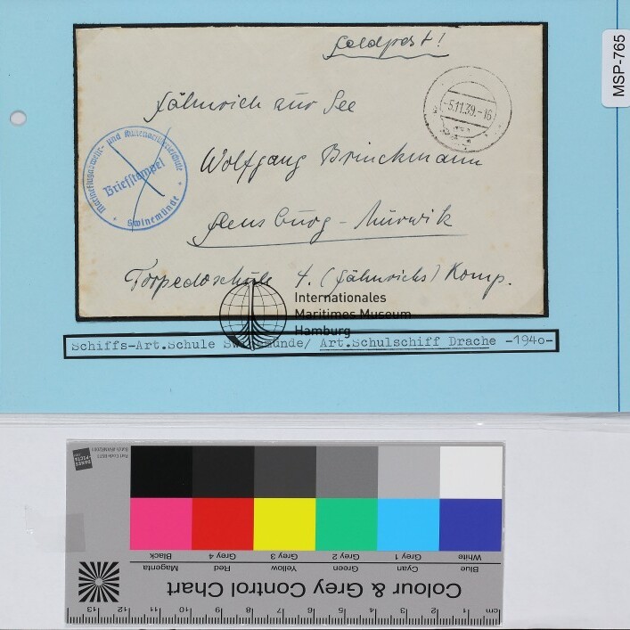 Handbeschriebener alter Briefumschlag mit rundem Poststempel und blauem Siegel auf blauem Archivkarton, Farbreferenzstreifen unten
