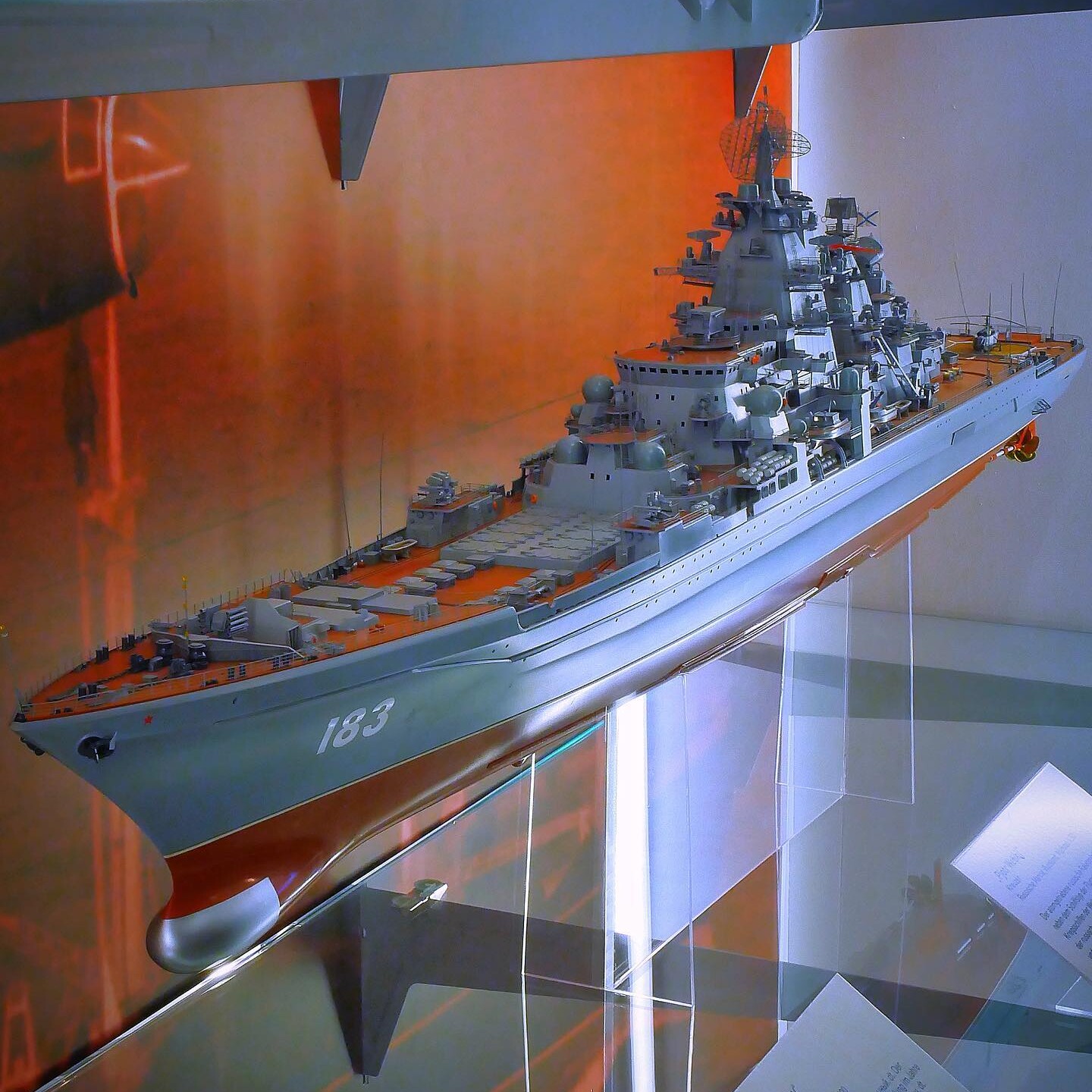 Detailliertes Modell eines grauen Kriegsschiffs mit der Nummer 183 auf dem Bug, auf Glasständern in einer Vitrine ausgestellt.