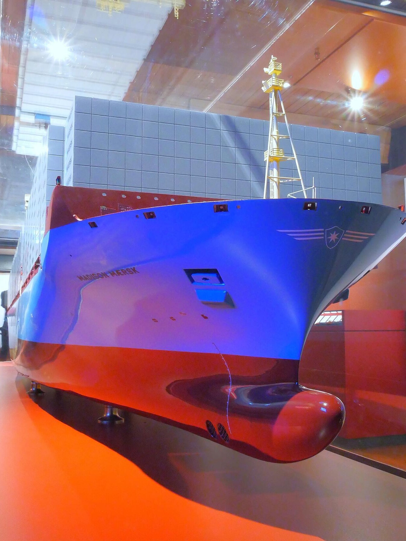 Bugansicht eines großen Containerschiff-Modells mit blau-rotem Rumpf, aufgestapelten Containerkästen und markantem Mast