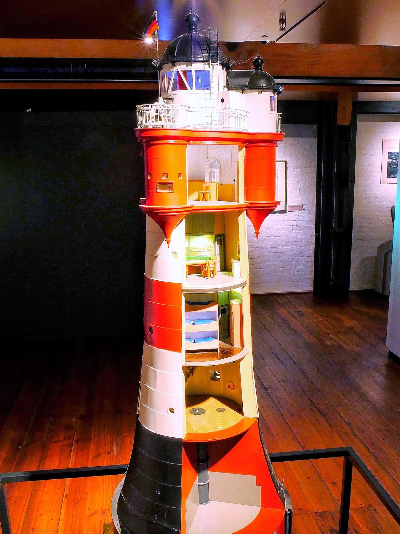 Detailliertes Schnittmodell eines rot-weißen Leuchtturms mit sichtbaren Innendecken, Zimmern, Treppen und Galerie im Museumsraum