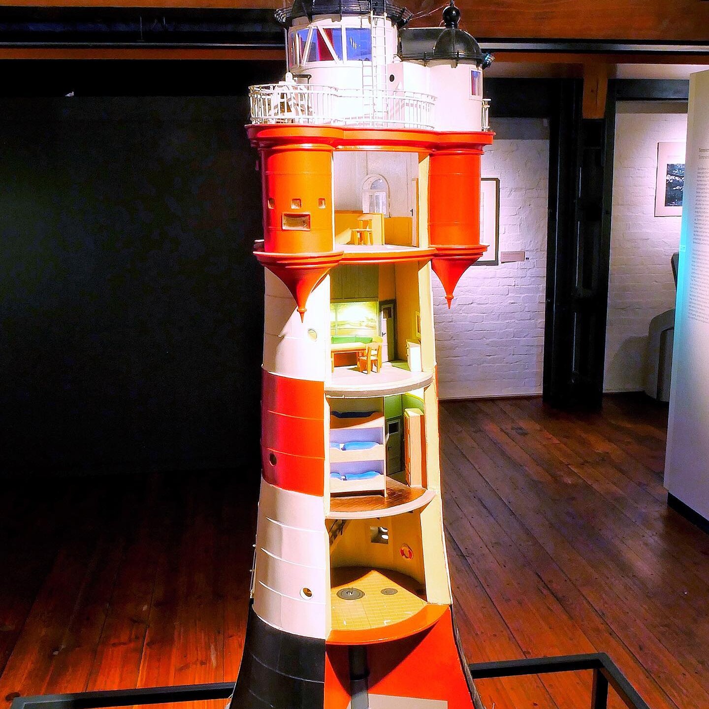 Detailliertes Schnittmodell eines rot-weißen Leuchtturms mit sichtbaren Innendecken, Zimmern, Treppen und Galerie im Museumsraum
