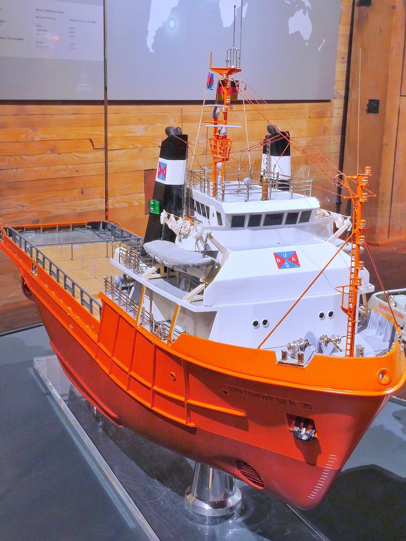 Modell eines orangen Rettungs- oder Forschungsschiffs mit weißer Aufbauten, Brücke, Masten und Decksdetails in einer Ausstellung.