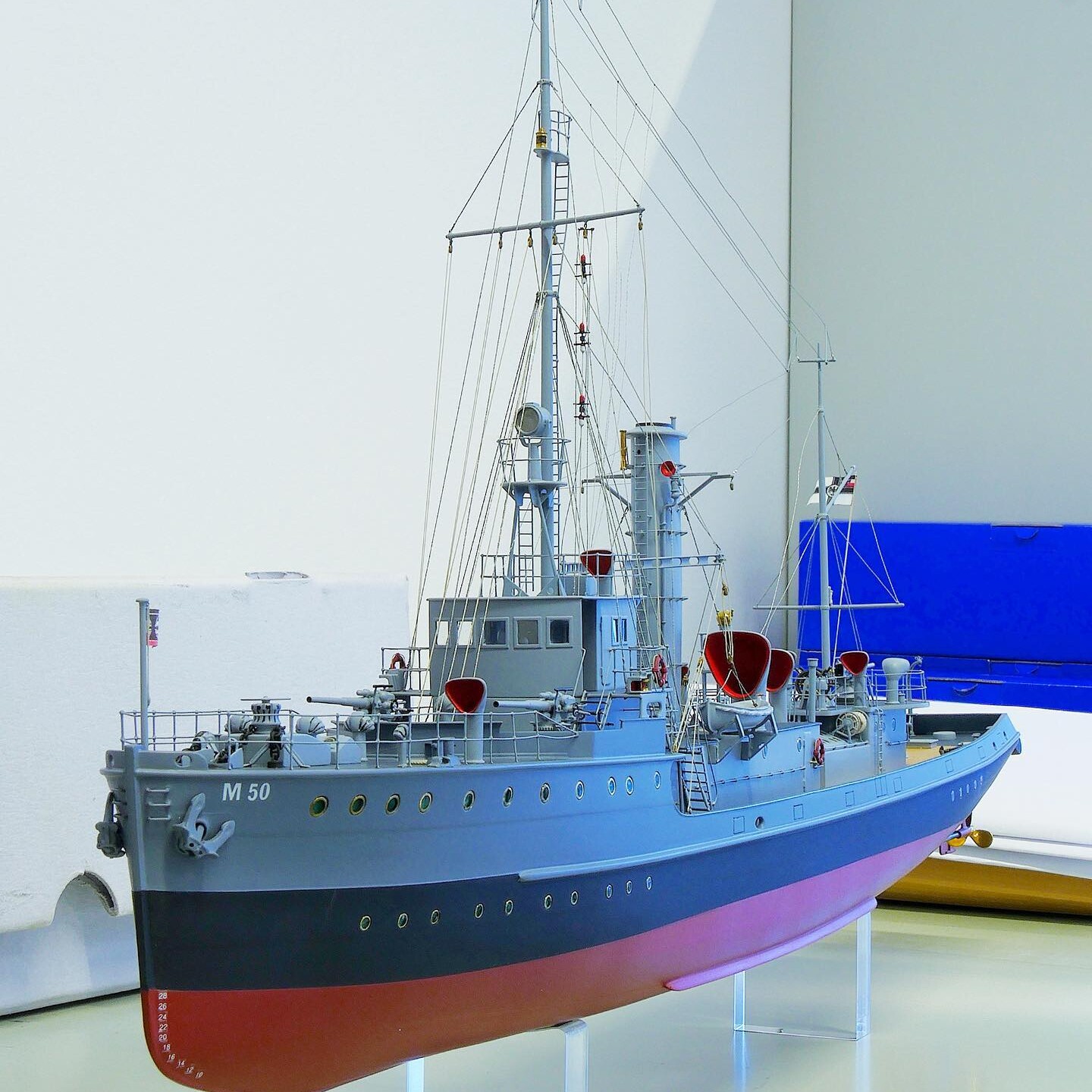 Detailliertes Modell eines graublauen Kriegsschiffs mit Mast, Takelage, Rettungsbooten und Bugnummer M50 auf Ständern