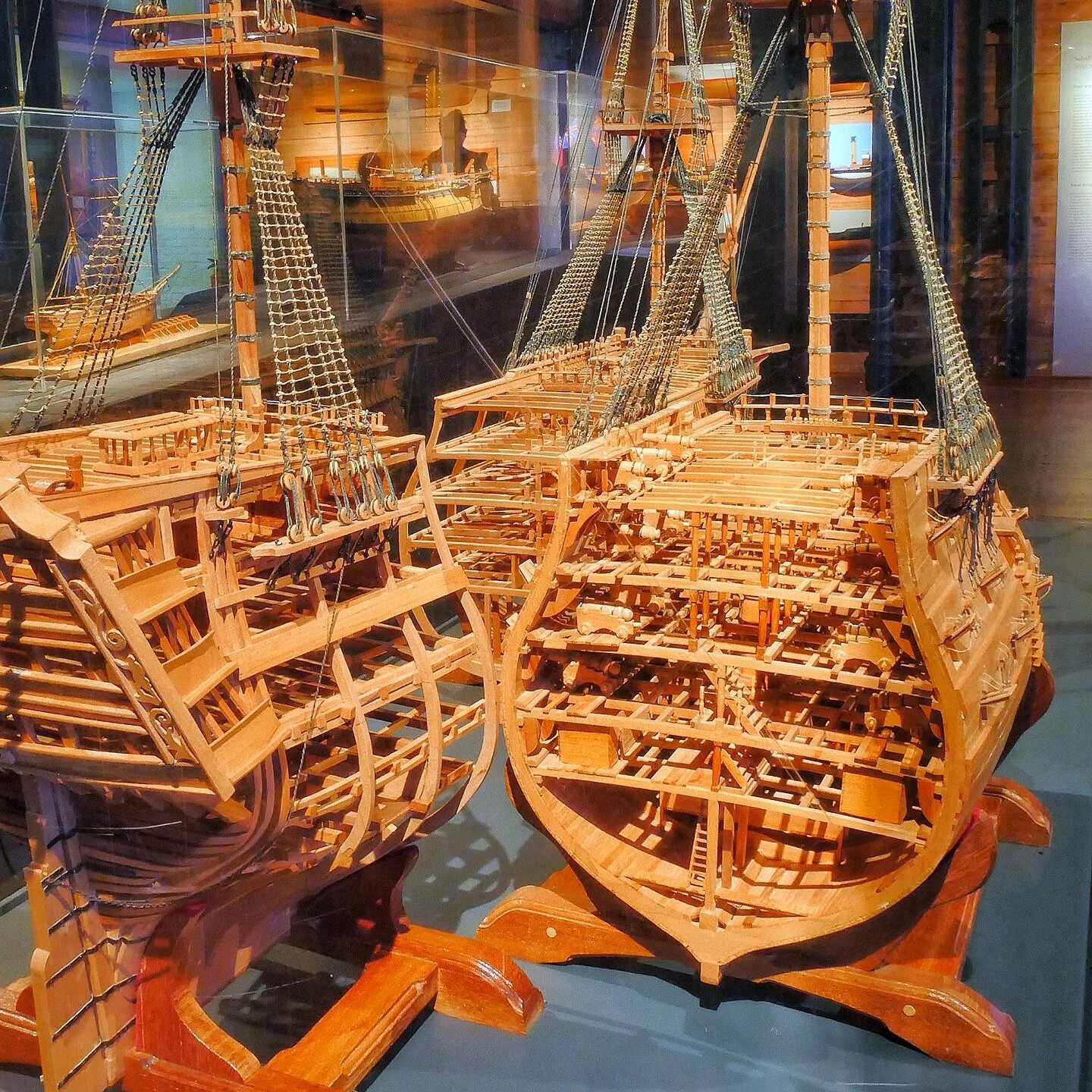 Zwei detaillierte Holzschiffsmodelle mit offener Spantenstruktur, Takelage und Takelnetz in einem Museumsvitrinen-Display.